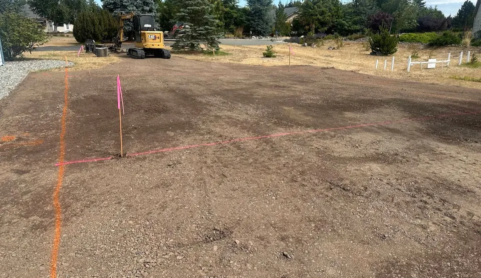 Cleared and graded building pad marked with survey paint and stakes by Holmes Earth Construction