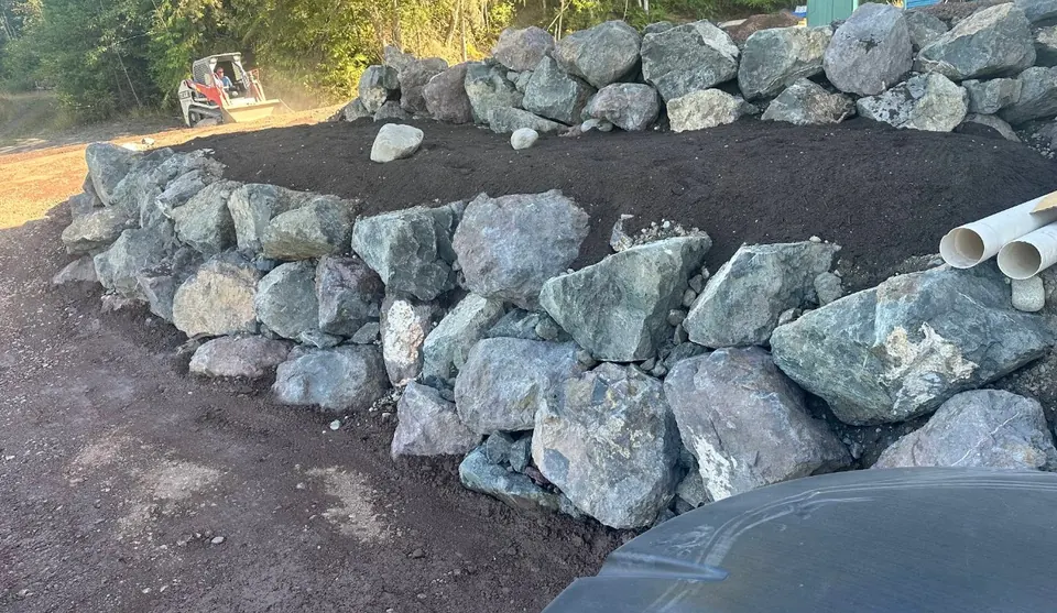 Boulder retaining wall with topsoil placed behind it by Holmes Earth Construction