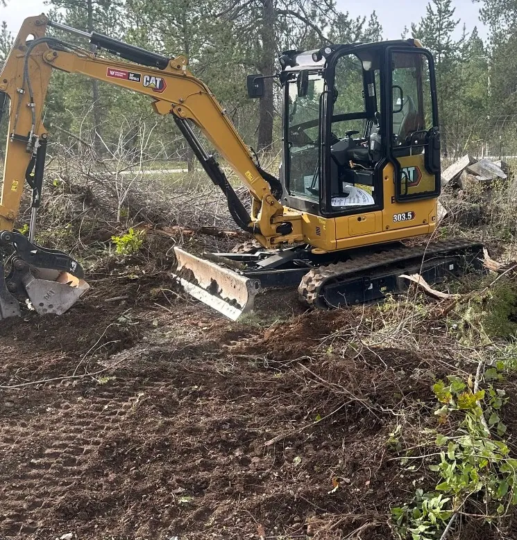 Mini excavator clearing brush and stumps on a rural property by Holmes Earth Construction