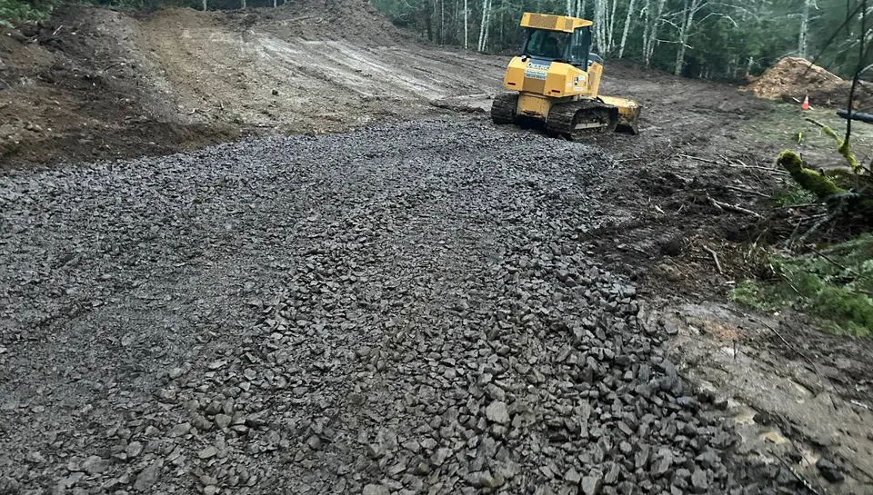 Dozer spreading crushed rock for a new driveway in the forest by Holmes Earth Construction