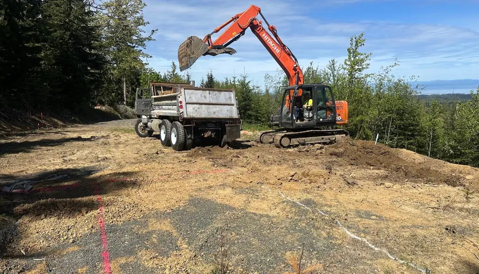 Excavator loading a dump truck during site grading with water views by Holmes Earth Construction