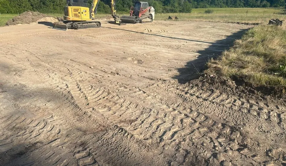 Mini excavator and track loader leveling a large dirt pad by Holmes Earth Construction