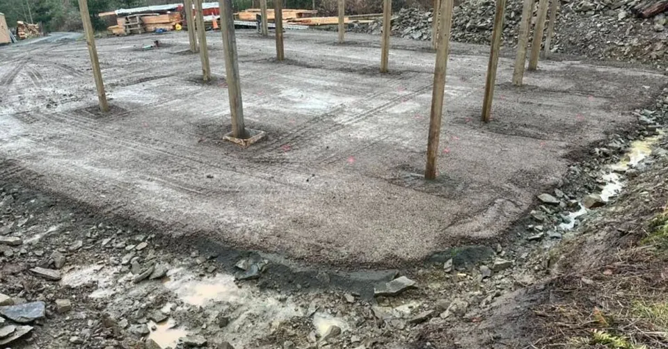 Pole building posts set on a graded gravel foundation pad by Holmes Earth Construction